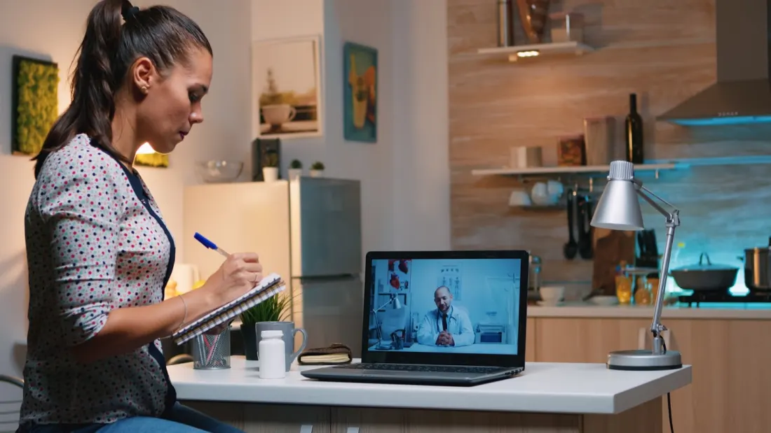 Patient taking notes during a telehealth visit.