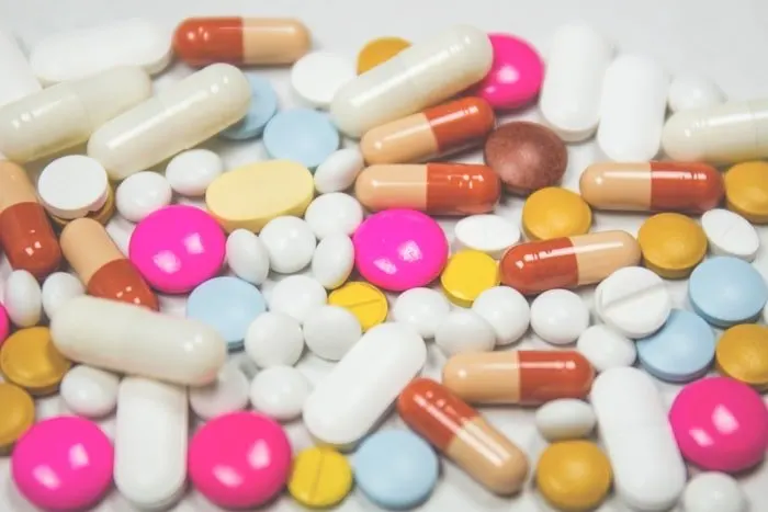 Assorted pills and capsules on a neutral surface.
